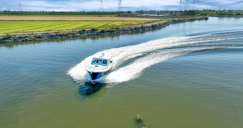 Slide: The Image of 2018 Back Cove 32 cruising on a scenic river with lush green fields. - 7