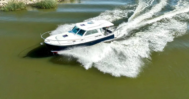 Slide: The Image of 2018 Back Cove 32 boat cruising on a calm waterway, creating a dynamic wake. - 9
