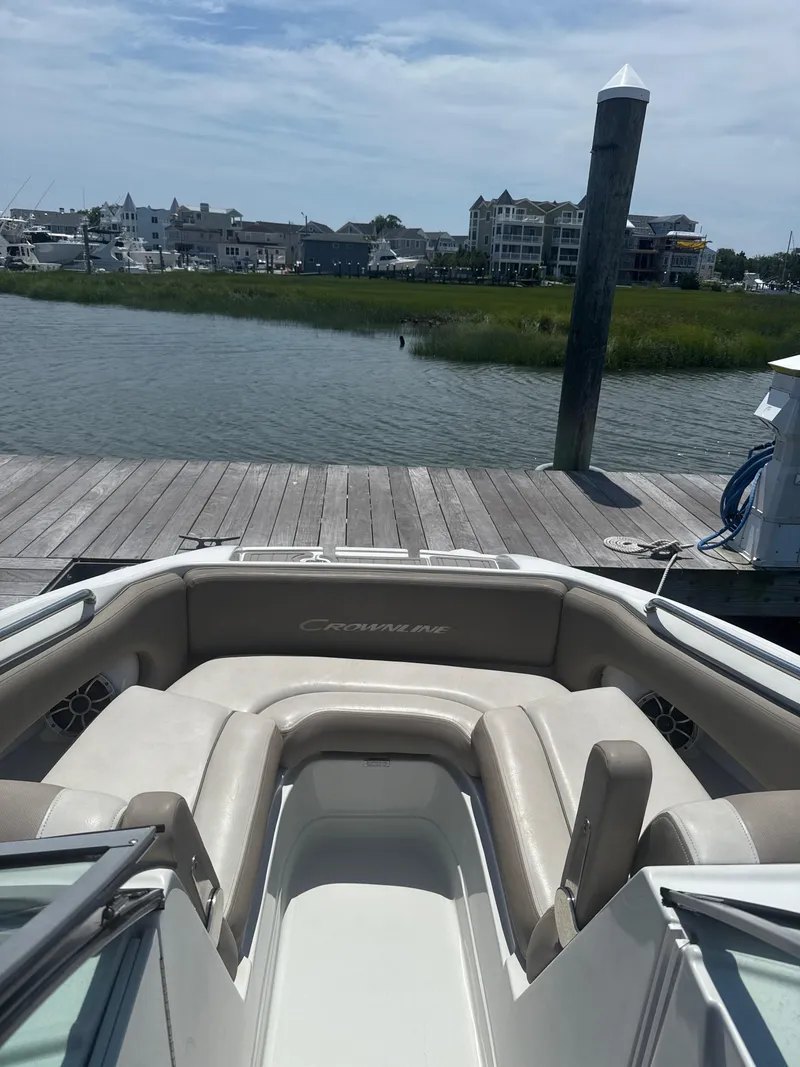 Slide: The Image of 2023 Crownline Eclipse E235 XS boat docked by a scenic waterfront. - 12