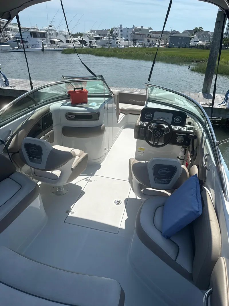 Slide: The Image of 2023 Crownline Eclipse E235 XS boat interior with seating and steering wheel, docked at marina. - 13