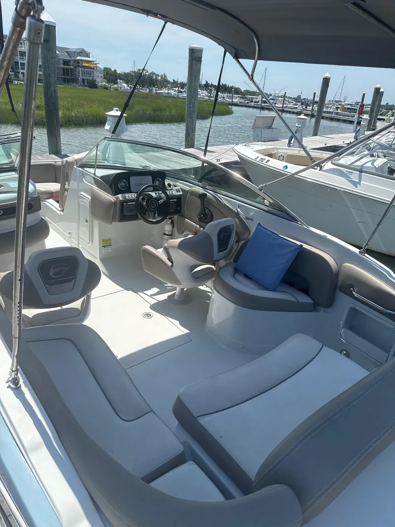 Slide: The Image of 2023 Crownline Eclipse E235 XS boat interior with seating and steering wheel at a marina. - 15