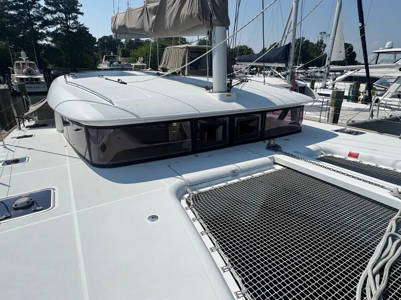 Slide: The Image of 2016 Lagoon 400 S2 catamaran docked, featuring spacious deck and netting. - 12