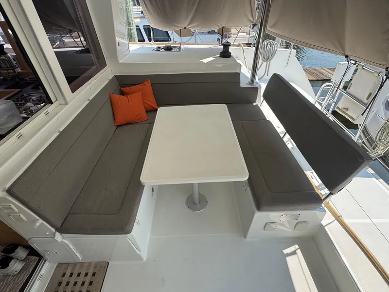 Slide: The Image of Cozy seating area on 2016 Lagoon 400 S2 catamaran with gray cushions and orange pillows. - 3