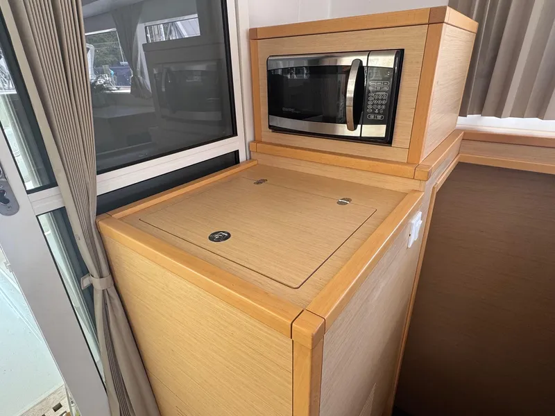 Slide: The Image of Microwave in 2016 Lagoon 400 S2 yacht kitchen, featuring wooden cabinetry and window view. - 32