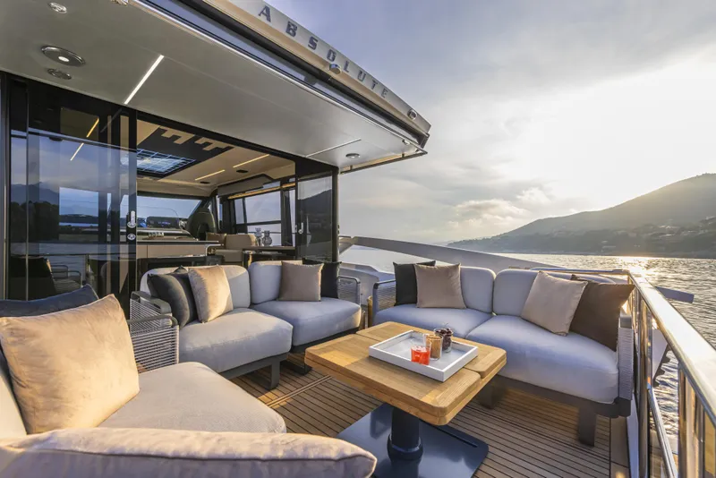 Slide: The Image of 2024 Absolute 48 Coupe yacht with luxurious outdoor seating area at sunset. - 5
