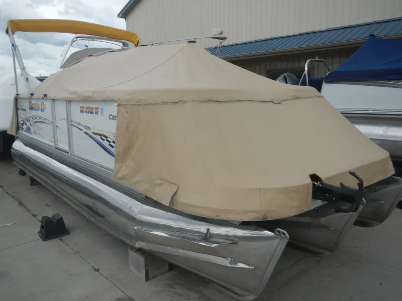 Slide: The Image of 2010 Crest Crest III pontoon boat with beige cover, docked outdoors. - 4