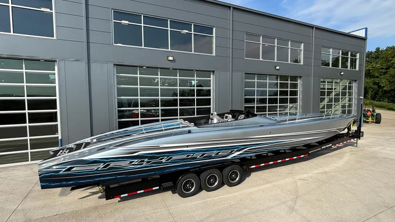 Slide: The Image of 2025 Outerlimits 50 SL Crypto II speedboat on trailer outside modern building. - 3