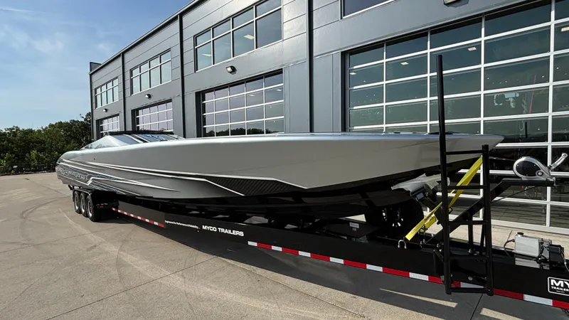 Slide: The Image of 2025 Outerlimits 50 SL Crypto II boat on trailer outside modern building. - 7