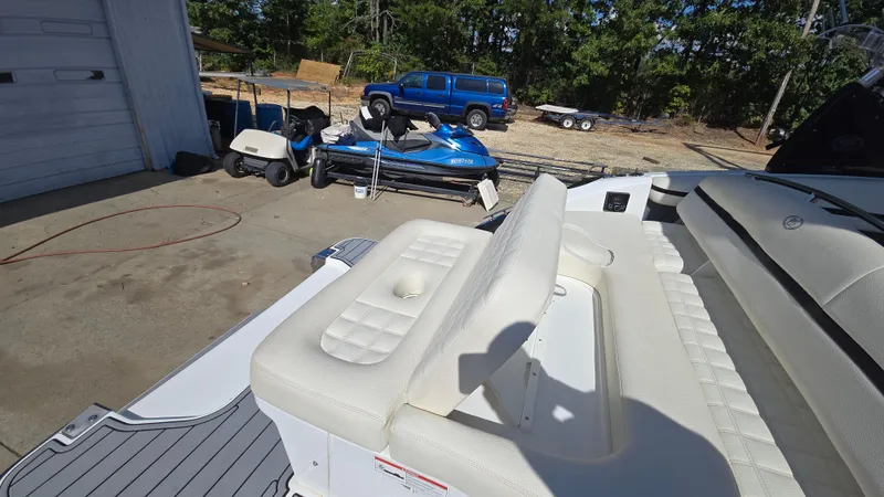 Slide: The Image of 2017 Cobalt R5 WSS Surf boat with white seating, parked near a garage and vehicles. - 16