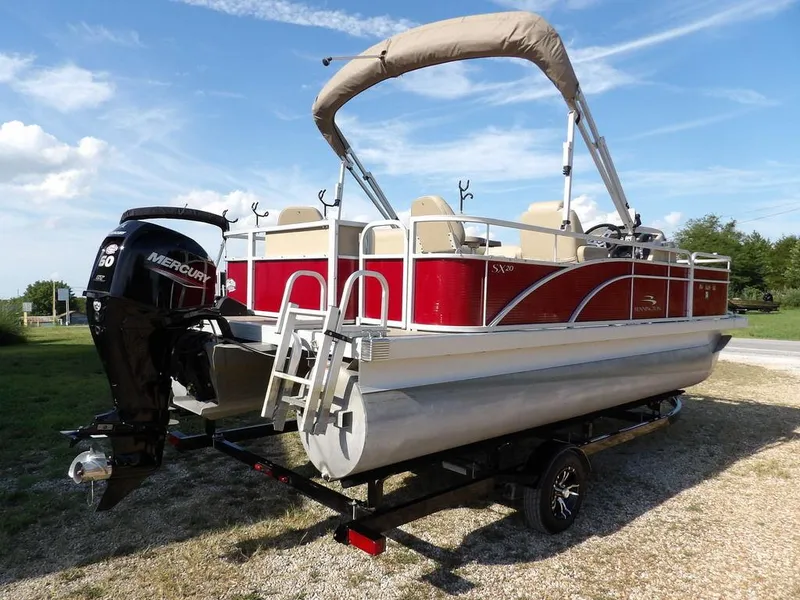Slide: The Image of 2015 Bennington 20 SFX pontoon boat with Mercury engine on trailer, parked outdoors. - 2