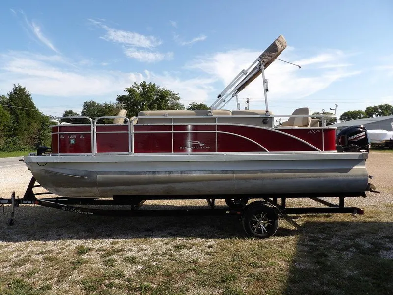 Slide: The Image of 2015 Bennington 20 SFX pontoon boat on trailer, red and silver design, parked outdoors. - 5
