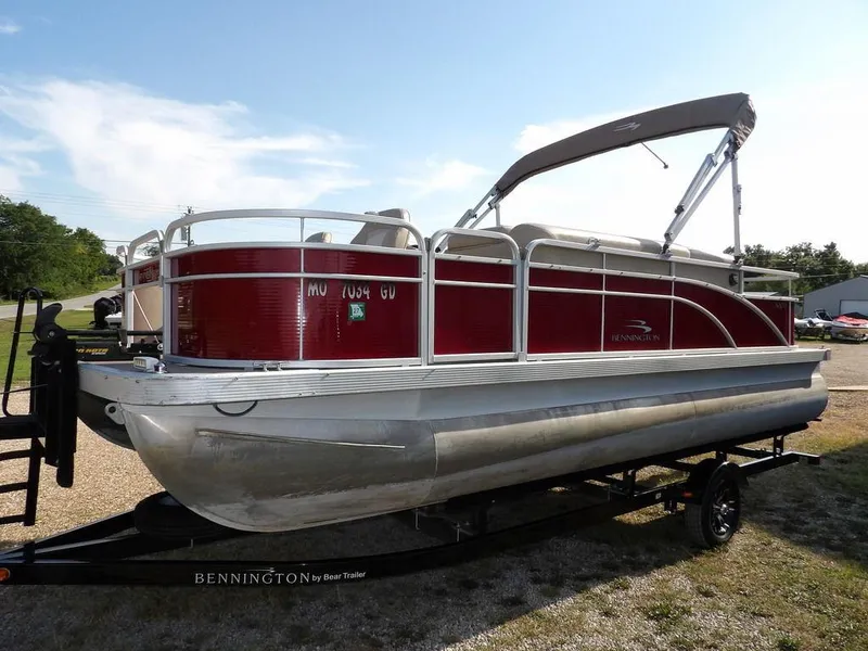 Slide: The Image of 2015 Bennington 20 SFX pontoon boat with red exterior on a trailer, under a clear blue sky. - 7