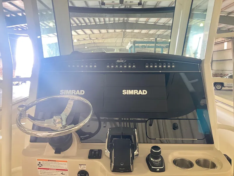 Slide: The Image of 2025 Boston Whaler 330 Outrage helm with Simrad electronics in a boat showroom. - 10