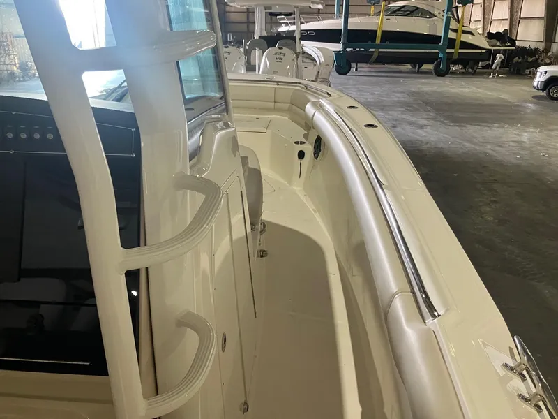 Slide: The Image of 2025 Boston Whaler 330 Outrage boat interior, showcasing sleek design and spacious layout in a warehouse. - 11