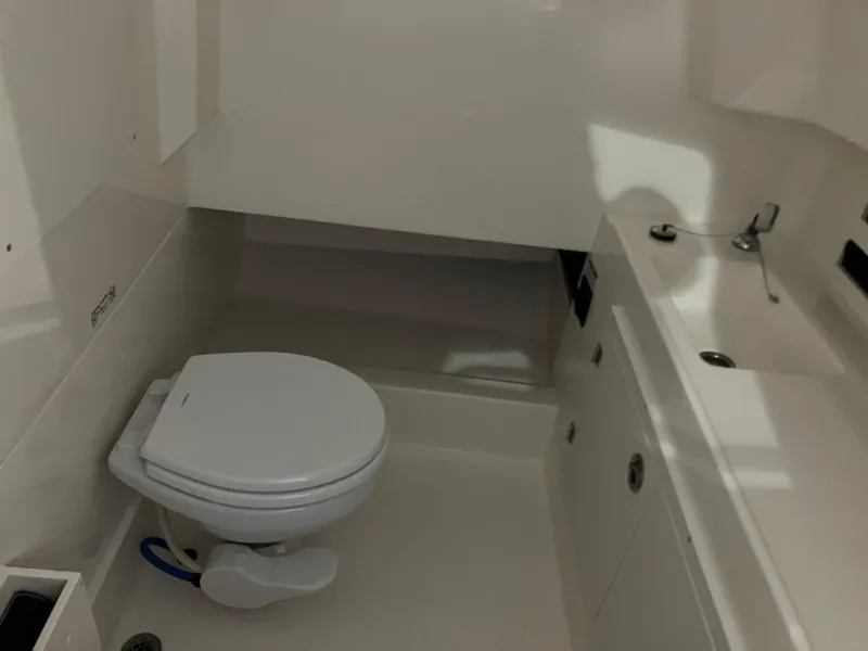 Slide: The Image of 2025 Boston Whaler 330 Outrage interior bathroom with toilet and sink. - 13