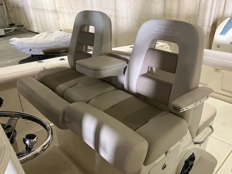 Slide: The Image of 2025 Boston Whaler 330 Outrage boat interior with plush seating and steering wheel. - 15