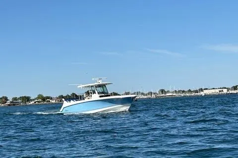 Slide: The Image of 2025 Boston Whaler 330 Outrage cruising on open water under clear blue skies. - 33