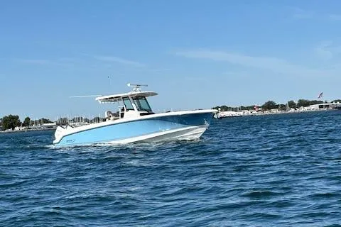 Slide: The Image of 2025 Boston Whaler 330 Outrage cruising on open water under clear blue skies. - 34