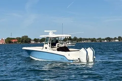 Slide: The Image of 2025 Boston Whaler 330 Outrage boat cruising on a calm lake under a clear blue sky. - 44
