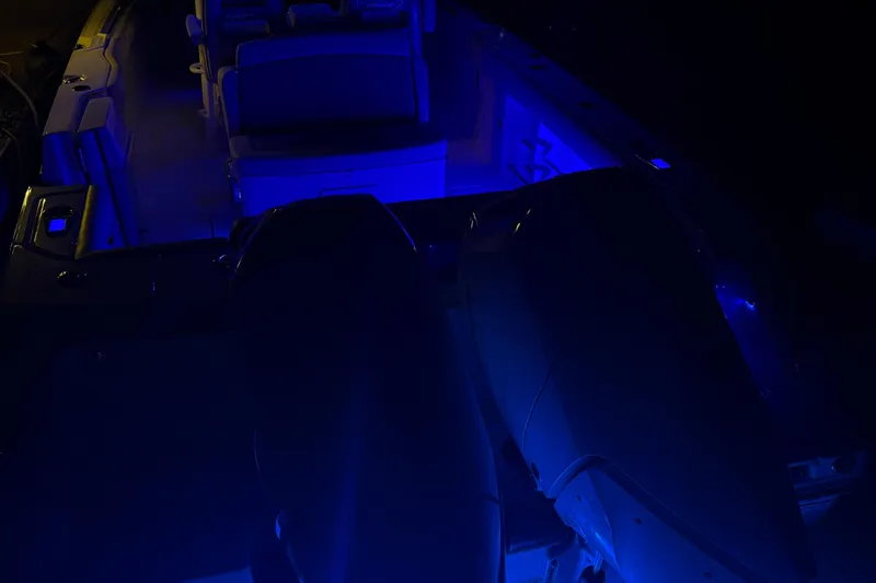 Slide: The Image of 2025 Boston Whaler 330 Outrage boat illuminated with blue LED lights at night. - 46