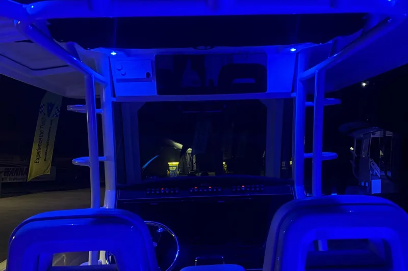 Slide: The Image of 2025 Boston Whaler 330 Outrage cockpit illuminated with blue LED lights at night. - 48