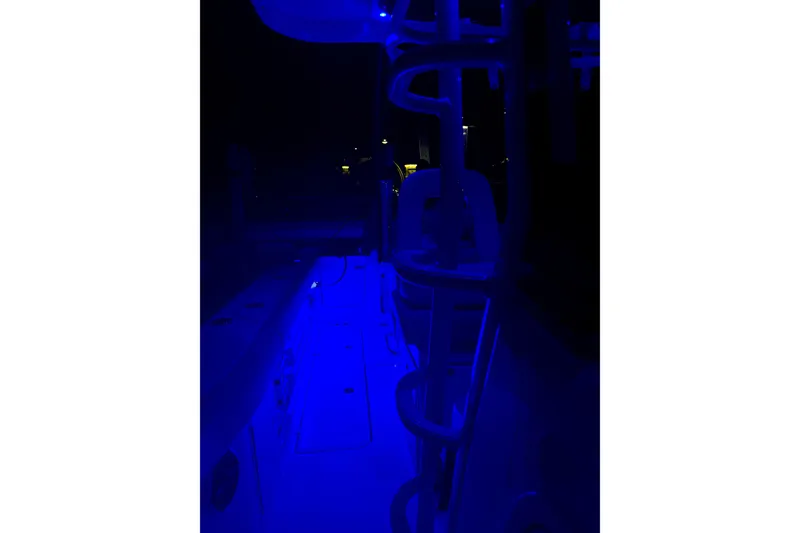 Slide: The Image of 2025 Boston Whaler 330 Outrage boat illuminated with blue LED lights at night. - 49