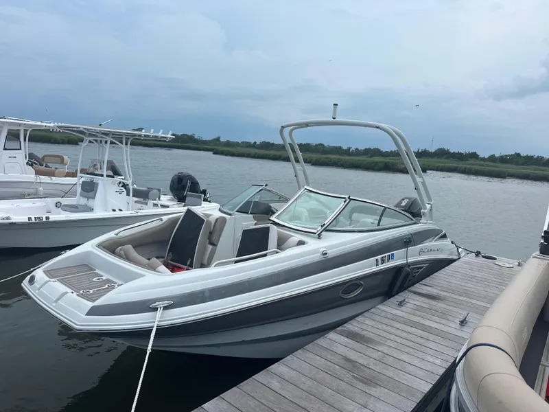 Slide: The Image of 2023 Crownline Eclipse E235 XS boat docked by the water. - 5