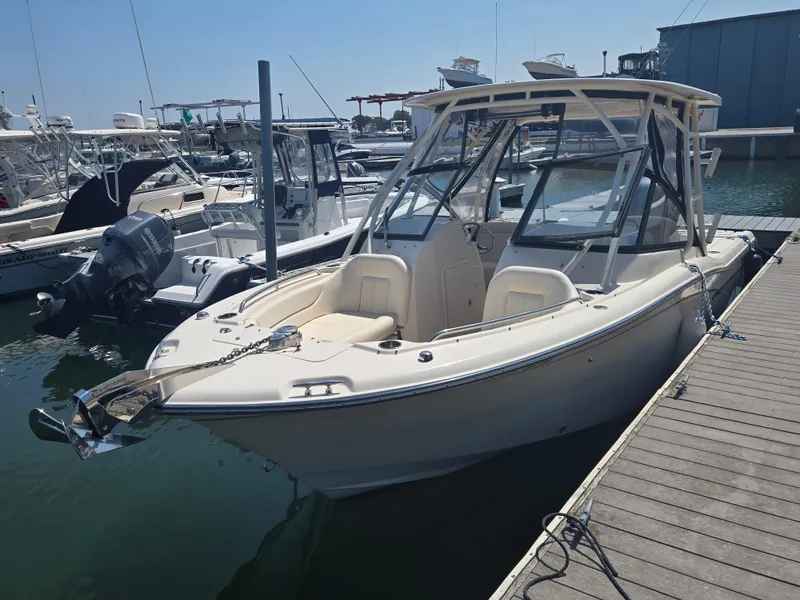 Slide: The Image of 2016 Grady-White Freedom 255 boat docked at a marina, showcasing sleek design and spacious seating. - 1
