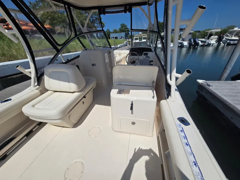 Slide: The Image of 2016 Grady-White Freedom 255 boat interior, featuring seating and helm, docked by the water. - 11