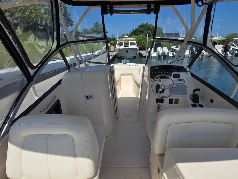 Slide: The Image of 2016 Grady-White Freedom 255 boat interior with helm and seating at a marina. - 2