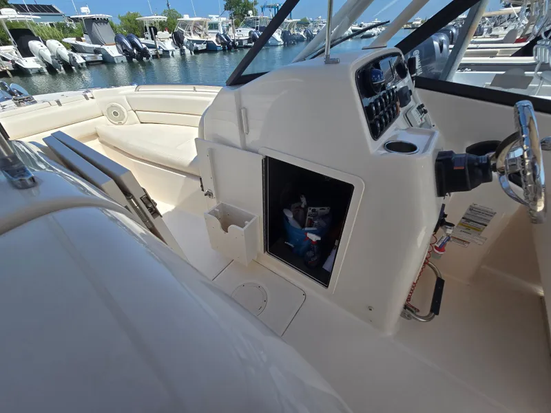 Slide: The Image of 2016 Grady-White Freedom 255 boat interior with helm and seating at marina. - 8