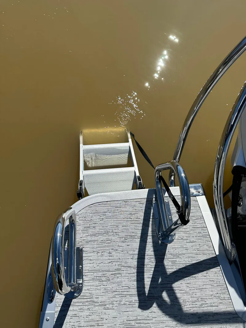 Slide: The Image of 2025 Bennington 23LFB boat ladder and deck, reflecting sunlight on water. - 13