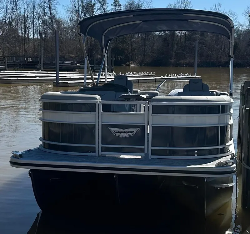 Slide: The Image of 2025 Bennington 23LFB pontoon boat docked on a calm lake with trees in the background. - 3