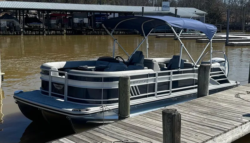 Slide: The Image of 2025 Bennington 23LFB pontoon boat docked with blue canopy and spacious seating. - 4