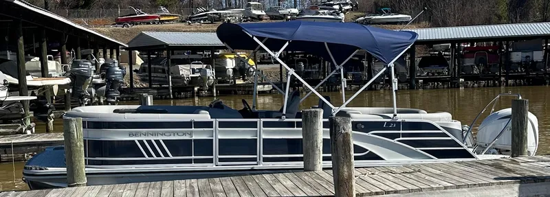 Slide: The Image of 2025 Bennington 23LFB pontoon boat docked with blue canopy and sleek design. - 5