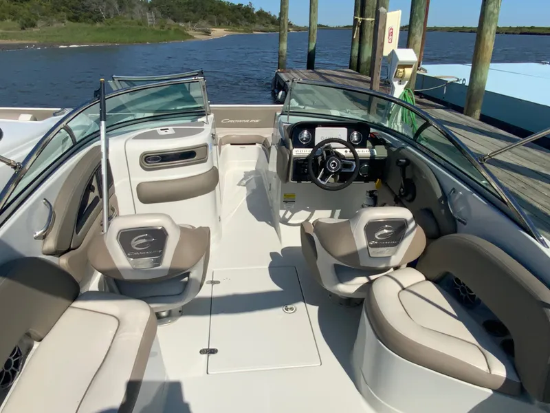 Slide: The Image of 2023 Crownline Eclipse E235 XS boat interior with seating and steering wheel, docked by the water. - 4