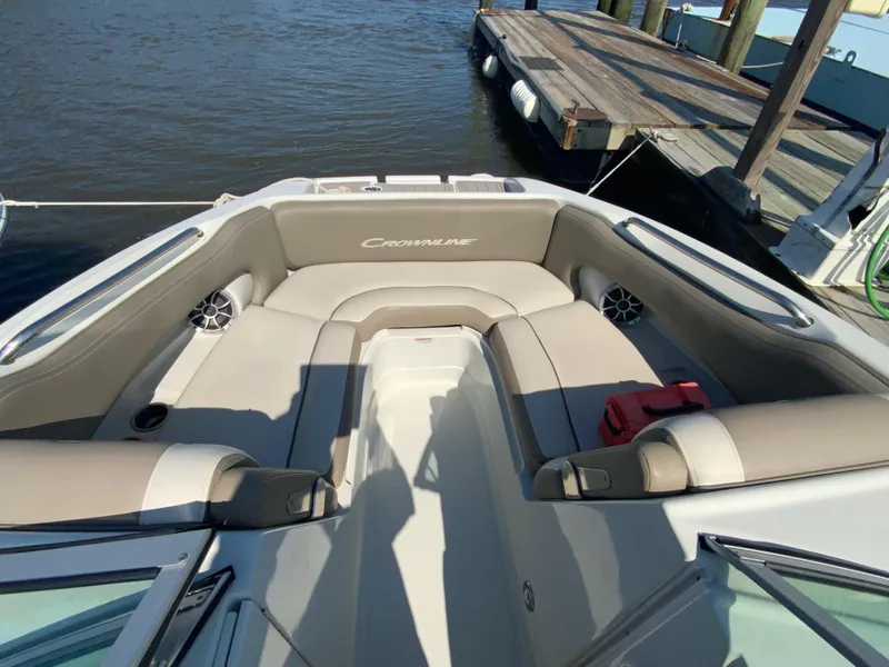 Slide: The Image of 2023 Crownline Eclipse E235 XS boat interior with beige seating, docked by the water. - 8