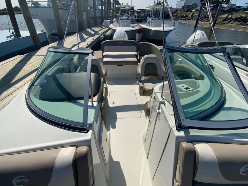 Slide: The Image of 2023 Crownline Eclipse E235 XS boat interior with seating and windshield, docked by the water. - 9
