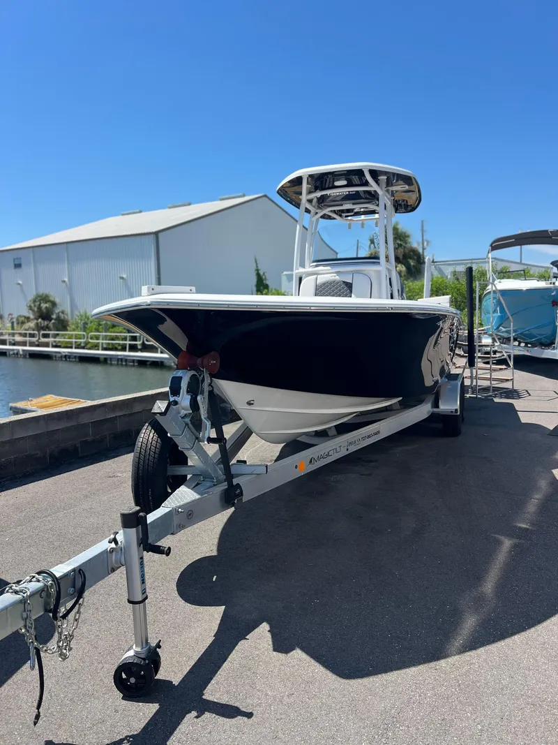 Slide: The Image of 2022 Tidewater 2500 Carolina Bay boat on trailer, parked outdoors under clear blue sky. - 4