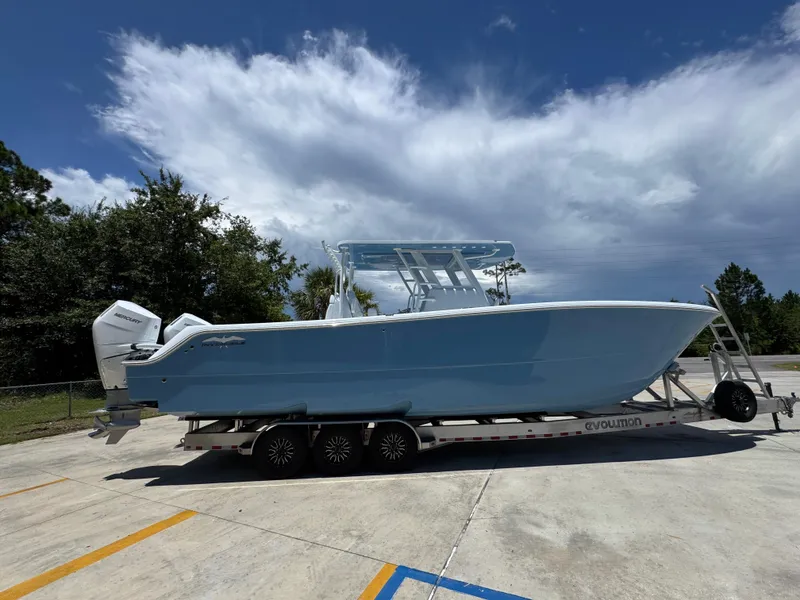 Slide: The Image of 2026 Invincible 33 Catamaran on trailer, parked outdoors under a partly cloudy sky. - 11