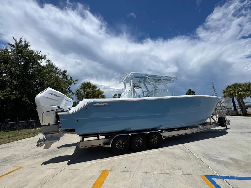 Slide: The Image of 2026 Invincible 33 Catamaran on trailer, parked outdoors under a partly cloudy sky. - 12