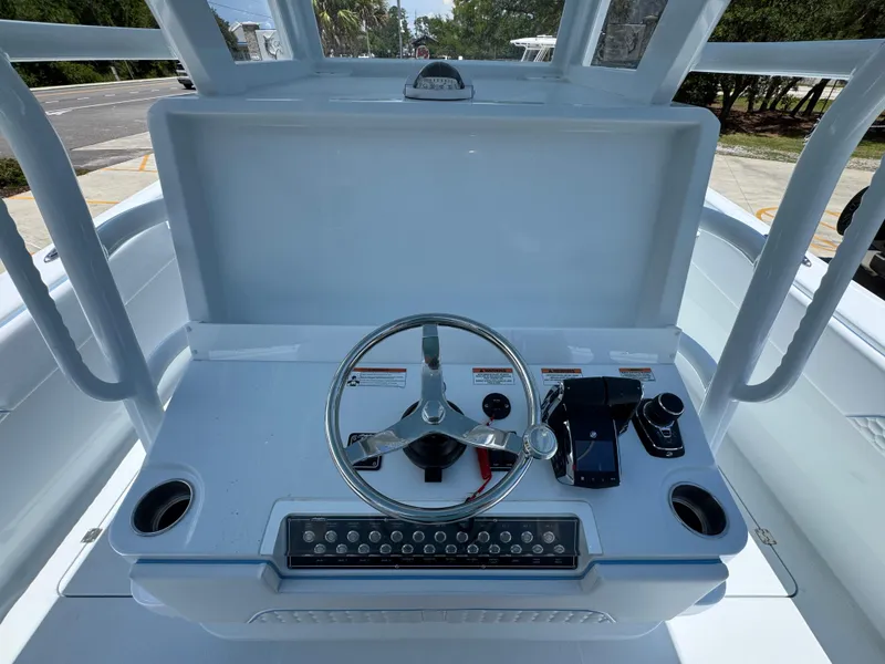 Slide: The Image of 2026 Invincible 33 Catamaran helm with steering wheel and controls, docked outdoors. - 32