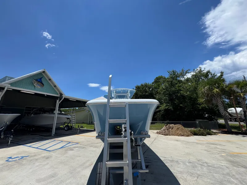 Slide: The Image of 2026 Invincible 33 Catamaran on trailer under clear blue sky at a boatyard. - 7