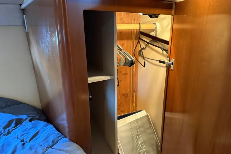 Slide: The Image of Wooden closet interior on a 2005 Meridian 341 Sedan yacht, featuring hangers and storage space. - 18