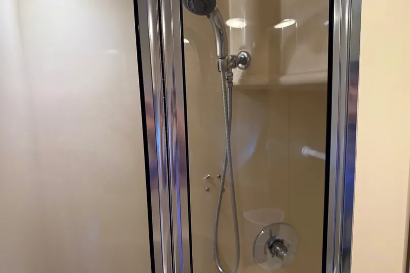 Slide: The Image of Shower area inside a 2005 Meridian 341 Sedan yacht, featuring a glass door and chrome fixtures. - 21