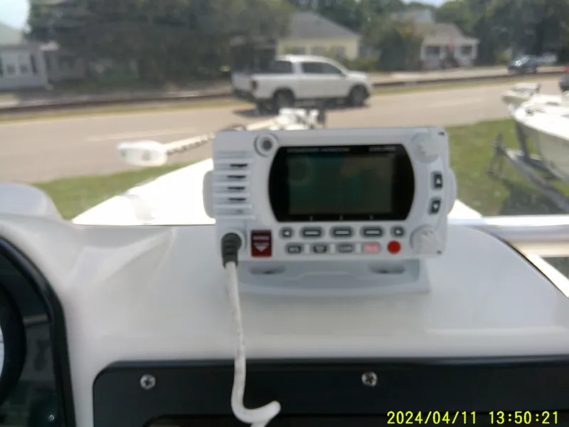 Slide: The Image of 2017 NauticStar 2140 Sport boat dashboard with marine radio, parked on a sunny day. - 24