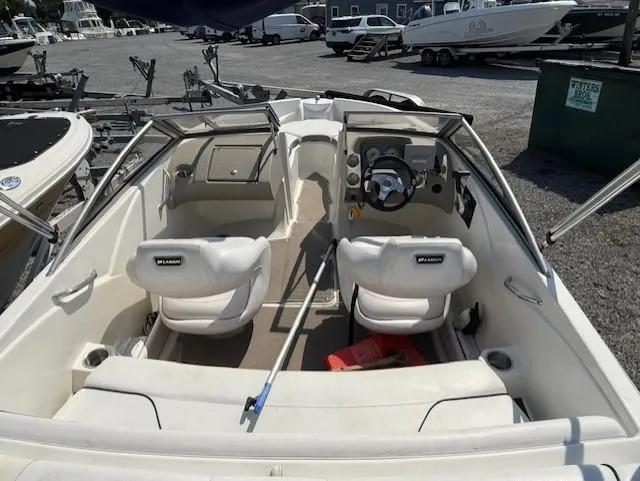 Slide: The Image of 2011 Larson LX 850 boat interior with steering wheel and seating, parked in a marina. - 5