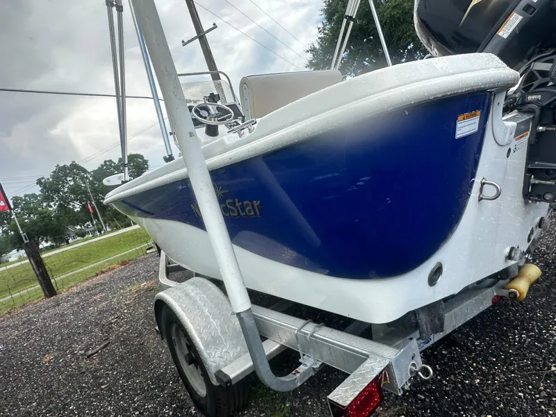 Slide: The Image of 2015 NauticStar 1810 NauticBay boat on trailer, blue and white hull, outdoor setting. - 7