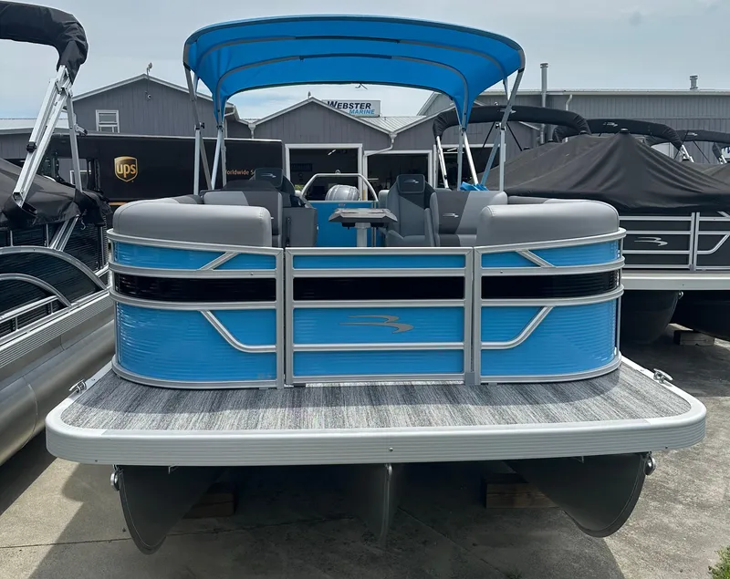 Slide: The Image of 2025 Bennington 22 SSR pontoon boat with blue exterior and canopy, docked at a marina. - 2