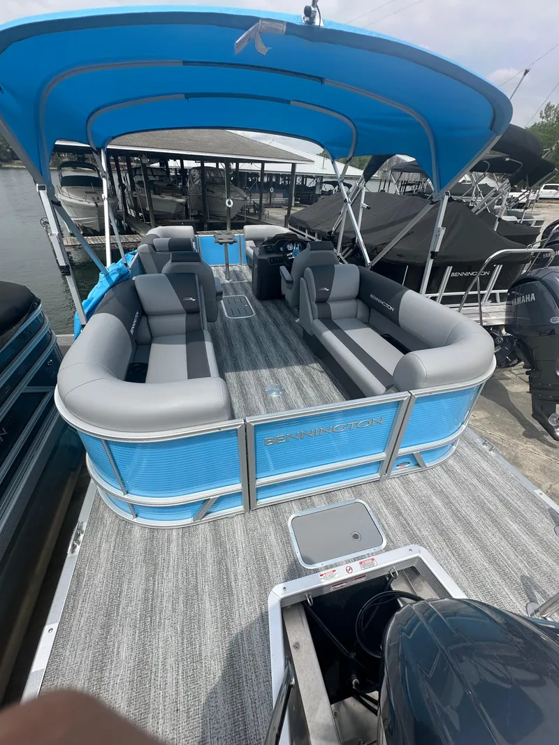 Slide: The Image of 2025 Bennington 22 SSR pontoon boat with blue canopy and gray seating at a marina. - 5